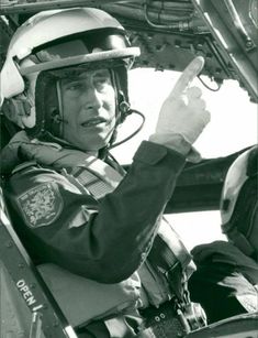 a man in the cockpit of an airplane with his hand up and pointing at something