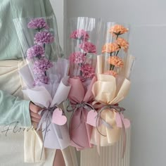 a person holding flowers in their hands and wrapped in plastic bags with ribbons on them