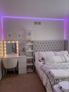 a bedroom with lights on the wall and a bed in front of a desk, mirror and chair