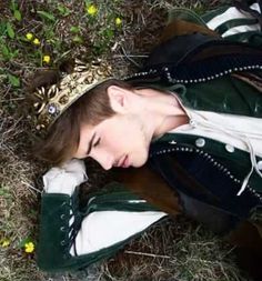 a woman laying on the ground with her head down wearing a green and white jacket