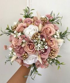 a bridal bouquet with pink and white flowers is held by a woman's hand