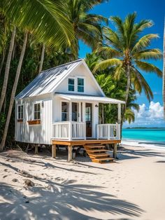 a small white house sitting on top of a sandy beach next to the ocean and palm trees