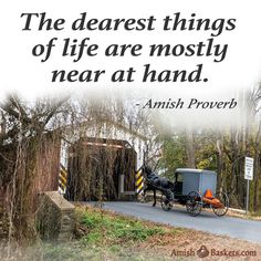 a horse drawn carriage driving down a road next to a covered bridge with the words, the dearest things of life are mostly near at hand