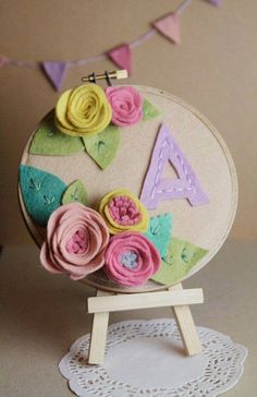 a handmade object with flowers on it sitting on top of a wooden easel