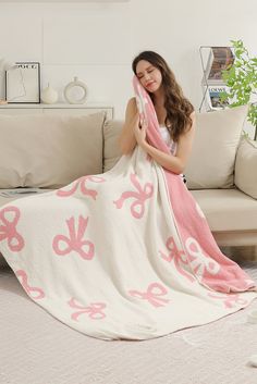 a woman is holding a pink and white blanket in her hands while sitting on a couch