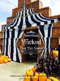 an entrance to a halloween themed building with pumpkins in the foreground and black and white striped awning