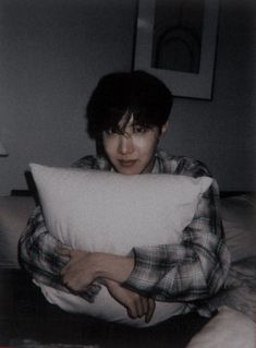 a woman sitting on a bed holding a pillow