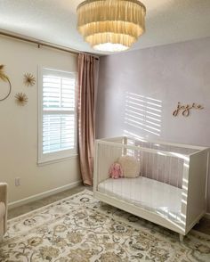 a baby's room with a crib, rocking chair and chandelier