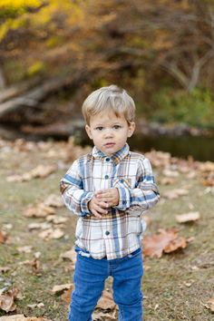 a little boy that is standing in the grass with his hands on his hips and looking at the camera