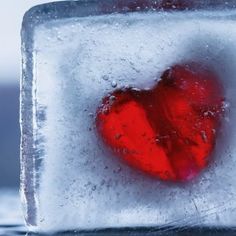 an ice cube with a red heart in it's center and water droplets around the edges