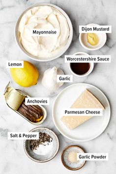 the ingredients needed to make this cheesecake are shown on a marble counter top, including lemons, parmesan cheese, garlic and mayonnaise