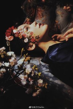 a woman laying down with flowers in her hair