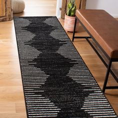 a black and white runner rug on a wooden floor next to a bench with succulents