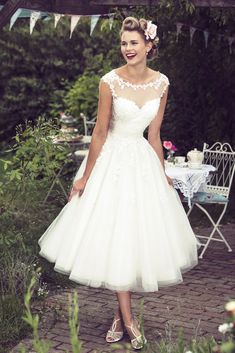 a woman wearing a white dress standing in the grass