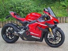 a red motorcycle parked on top of a gravel road