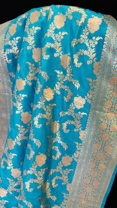 Embrace ethereal elegance with our Sky Blue Katan Silk Saree adorned with lustrous gold zari. Crafted with the finest Katan silk, this saree exudes a subtle charm that is both modern and timeless. The sky blue hue is a refreshing departure from traditional shades, offering a contemporary twist to the classic Banarasi aesthetic. The intricate gold zari work adds a touch of opulence, creating a mesmerizing interplay of light and shadow. The saree drapes effortlessly, accentuating the wearer's silh Luxury Dola Silk Saree With Zari Work, Luxury Banarasi Silk Shawl For Festivals, Luxury Bollywood Katan Silk Traditional Wear, Luxury Banarasi Silk Dupatta With Resham Embroidery, Luxury Katan Silk Pre-draped Saree With Self Design, Luxury Katan Silk Shawl For Wedding, Luxury Zari-work Katan Silk Embroidered Fabric, Luxury Katan Silk Fabric With Zari Work, Luxury Katan Silk Fabric With Zari Embroidery