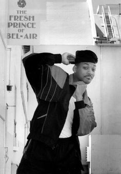 a black and white photo of a man holding a sign that says the fresh prince of bel - air