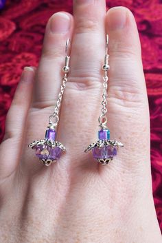 a pair of purple and blue earrings on someone's hand