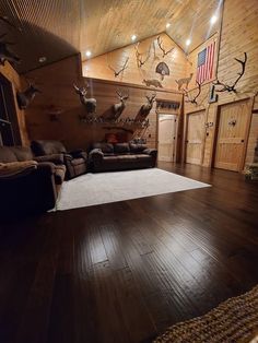 a living room with wood floors and deer heads on the wall