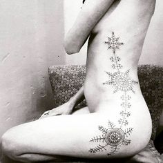 a woman is sitting on the couch with her back turned to the camera and has tattoos on her body