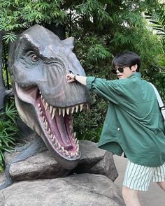 a man standing next to a statue of a dinosaur with it's mouth open