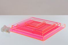 a pink and orange box with three sections on top, sitting on a white surface