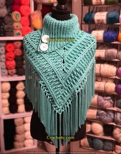 a knitted shawl with buttons on it in front of yarns and crochet