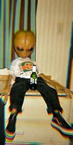 an alien sitting on top of a couch next to a bottle of beer in his hand