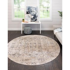 a round rug in a living room with white walls and wood flooring on the side