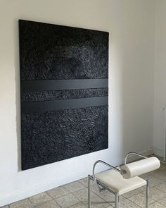 a white chair sitting in front of a large black piece of art on the wall