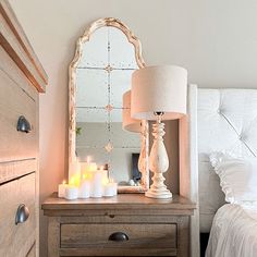 a bedroom with a dresser, mirror and lit candles on the night stand in front of it