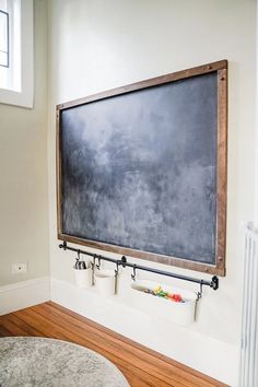 a chalkboard mounted to the wall in a room with wooden floors and white walls