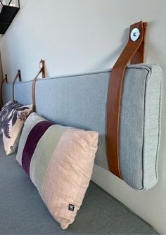 the pillows are lined up against the headboard with leather straps on each one side