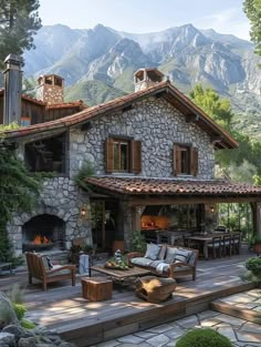 a stone house with outdoor furniture and mountains in the background