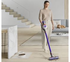 a woman with a vacuum mop in her hand standing next to a cat on the floor