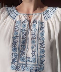 "Vintage 70-80ss folk style Hungarian traditional white blouse. Peasant blouse with floral hand embroidery in blue colours. Smocked neckline blouse. Traditional Hungary Matyo embroidery. Ethnic blouse. M size. From shoulder to shoulder 16\"41cm Armpit to armpit 48\"122cm Sleeve length 14\"36cm Length 24\"61cm." Embroidery Blouses, Handmade Folk Blouse For Summer, Handmade White Blouse For Spring, Handmade Folk Style Blouse For Spring, Handmade Folk Blouse For Spring, Handmade Folk Style Spring Blouse, Traditional Blue Peasant Top With Floral Embroidery, Fitted Folk Blouse With Floral Embroidery, Folk Style Blue Peasant Top With Floral Embroidery