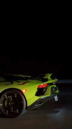 a yellow sports car in the dark with its lights on