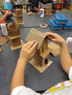 a group of children sitting around a table making cardboard houses