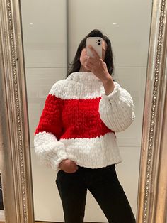 a woman taking a selfie in front of a mirror wearing a red and white sweater