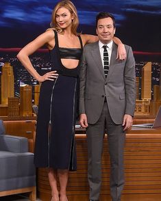 a man and woman standing next to each other in front of a tv screen with the tonight show logo on it