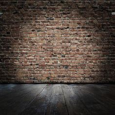 an empty room with brick wall and wooden floor in the foreground, there is only one light on