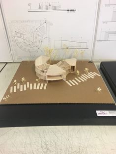 a model of a building on top of a cardboard box in front of a drawing