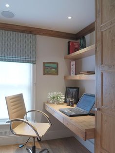 a laptop computer sitting on top of a wooden desk next to a chair and window