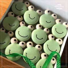 a box filled with lots of green cookies covered in frosting and smiling faces on top of each other