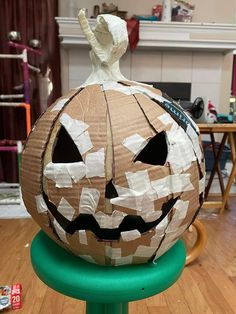 a paper mache pumpkin sitting on top of a green stool