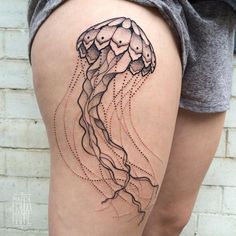 a woman's thigh with a jellyfish tattoo on it