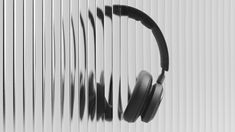 black and white photo of headphones on the side of a wall with vertical blinds