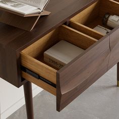 an open drawer on a desk with books and magazines in the bottom section, next to a book