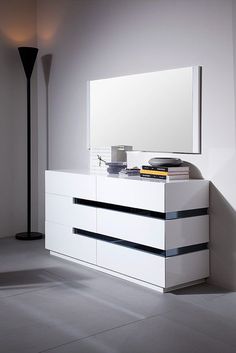 a white dresser sitting next to a lamp in a room with a mirror on it