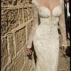 a woman in a wedding dress standing next to a stone wall